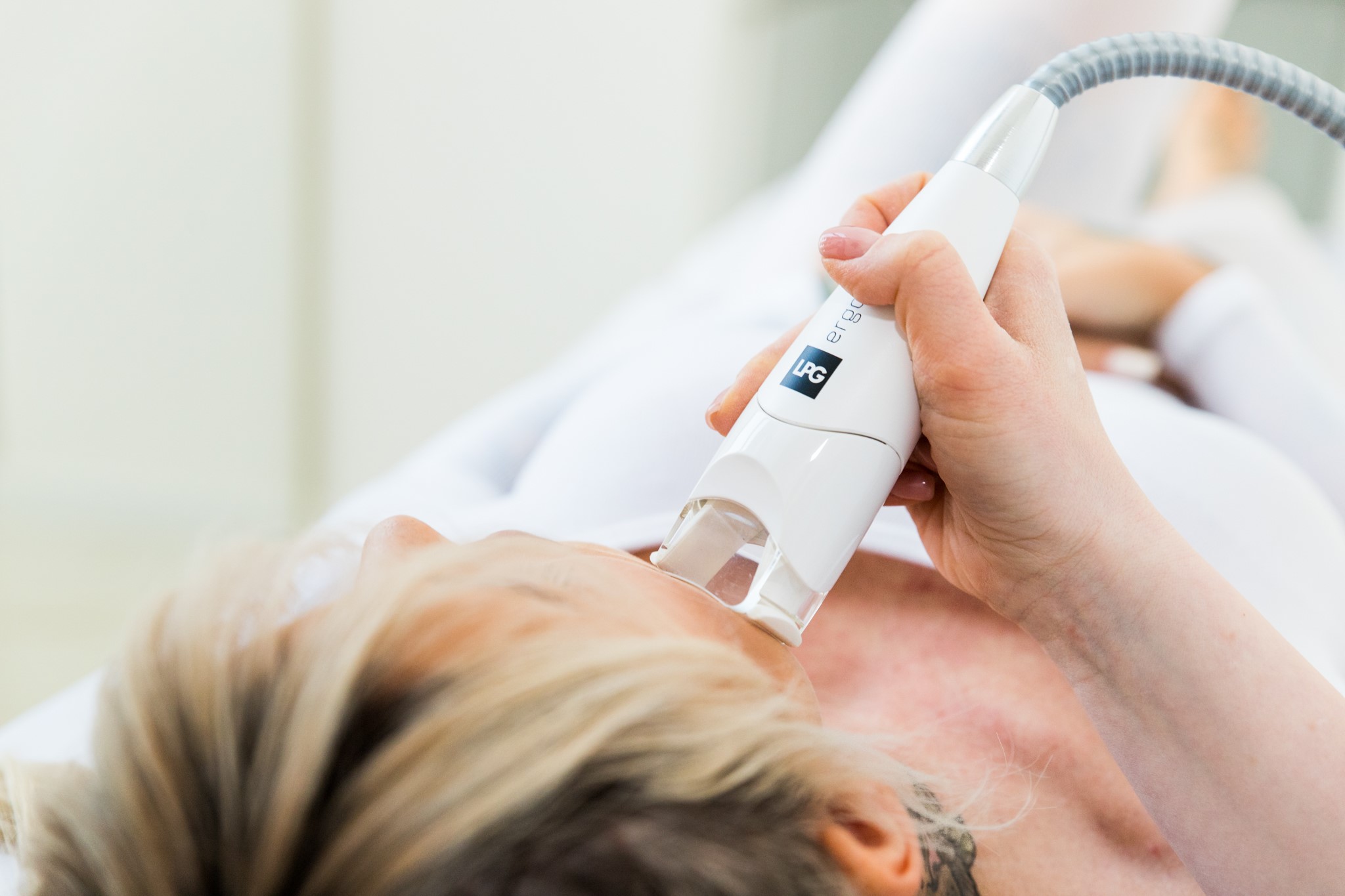 Zabieg pielęgnacyjny twarzy wykonywany urządzeniem LPG, klientka w pozycji leżącej podczas terapii