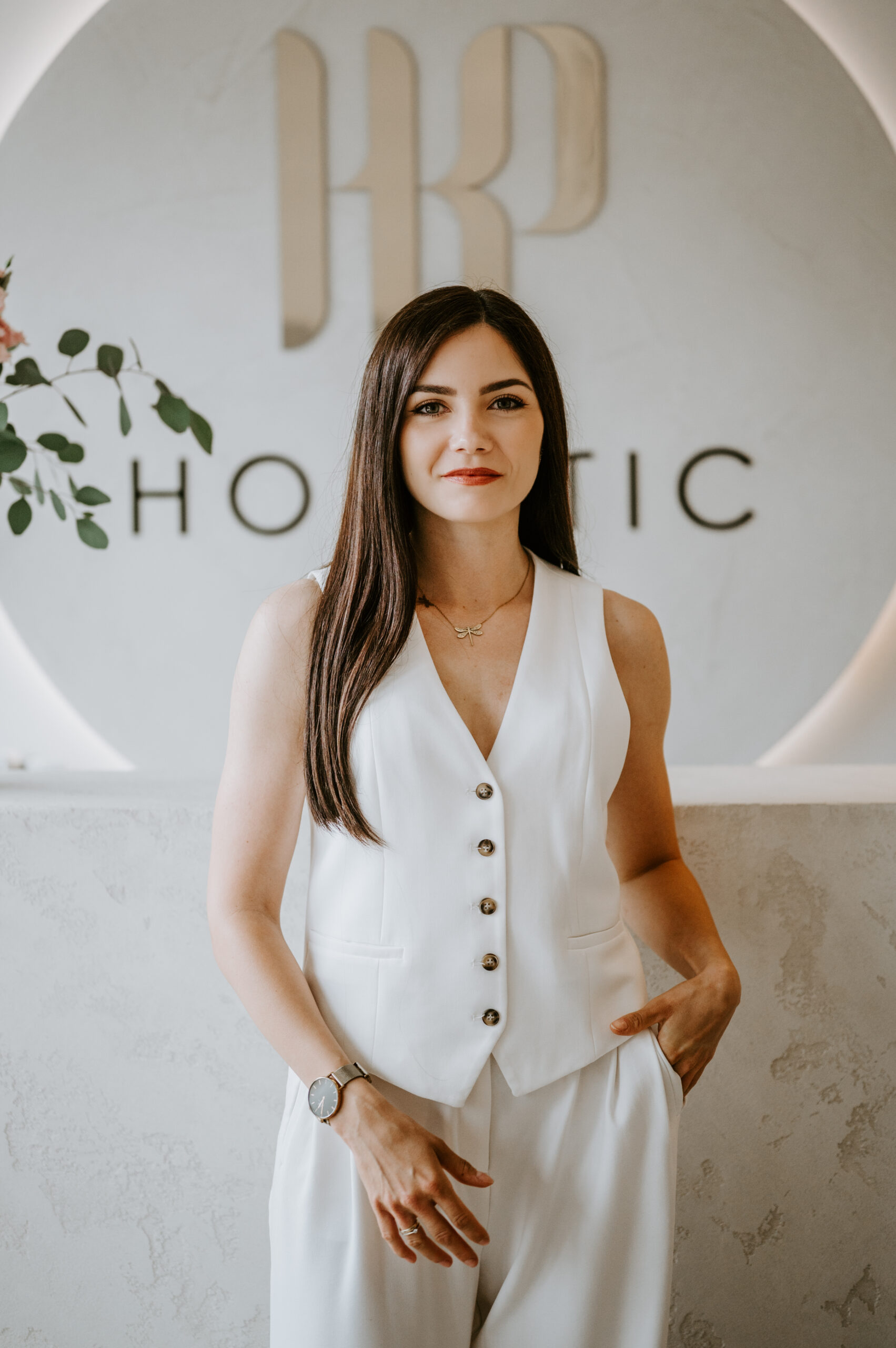 Specjalistka kosmetologii holistycznej stojąca w recepcji gabinetu wellness, elegancka przestrzeń i naturalny wystrój